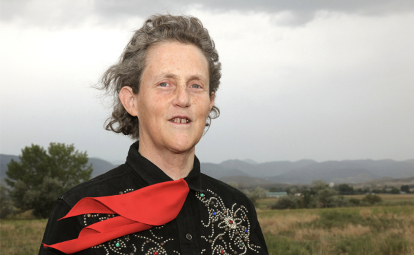 An image of author and activist Dr. Temple Grandin; a white woman with grey hair wearing a black highly-decorated top and red ascot